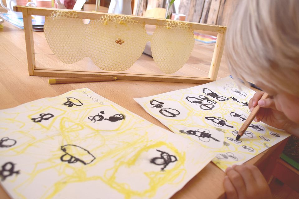 Honigwaben im Rahmen und Kinderzeichnungen von Bienen